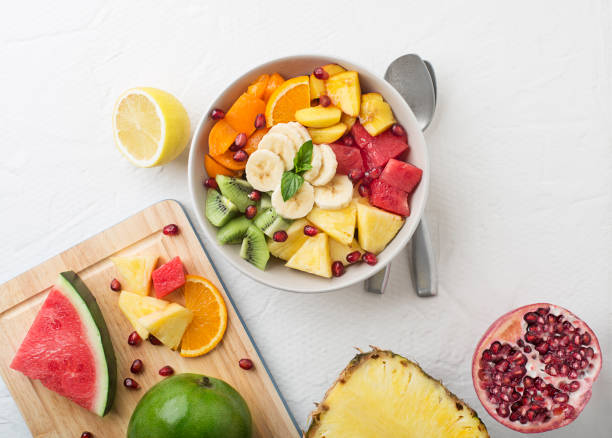 Bowl of healthy fresh fruit salad on white background, top view